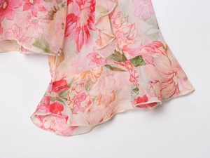 Dettaglio ravvicinato della camicia in chiffon a fiori rosa con volant e motivi vivaci