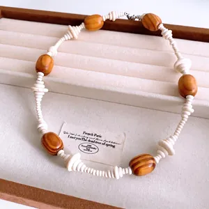 Retro ethnic style necklace with oval wood beads and white stone pendant on beige tray