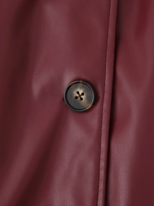 Gros plan sur la texture du cuir bordeaux et le bouton en écaille du trench