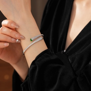 Detailed view of silver open cuff bracelet with pavé zircons and green emerald accents
