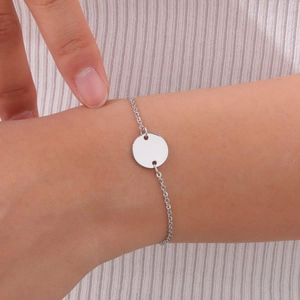 Close-up of minimalist silver stainless steel bracelet with a round blank charm on wrist