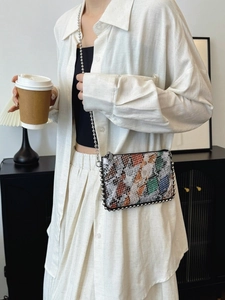 Crossbody envelope bag with snake pattern patchwork and silver bead chain strap on model