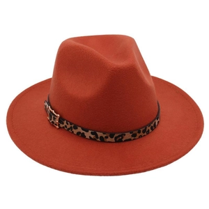 Detail of the leopard print band and golden buckle on a brick red wool fedora hat