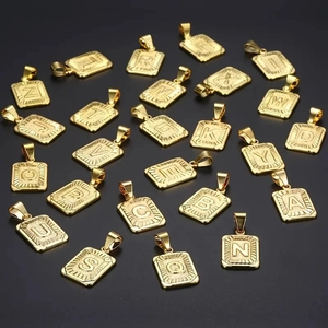 Vista piana di 21 ciondoli rettangolari placcati oro 18k con iniziali su nero