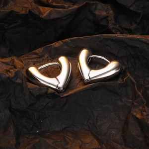 Polished heart-shaped silver earrings on black background with elegant light reflection