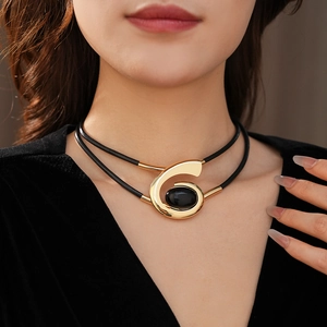 Close-up of double-layer choker with gold spiral pendant and black oval gemstone