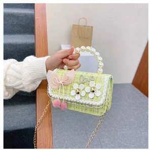 Detail of child handbag with pearl handle, pink bow and tweed fabric in light green