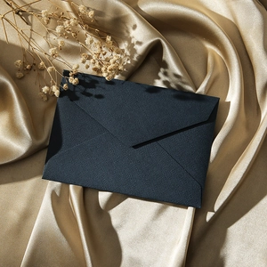 Detail of dark blue textured linen envelope on elegant gold silk with dried flowers