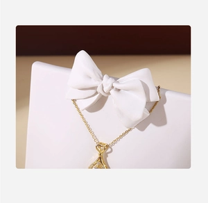 Close-up of gold water drop pendant necklace on resin butterfly bow jewelry stand