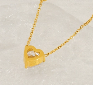 Detail of a golden heart pendant with a pear-cut zircon on a delicate O-chain necklace