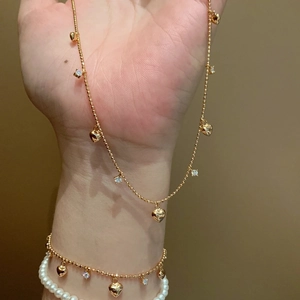 Set collana con cuore dorato e bracciale di perle con cristalli brillanti sulla mano