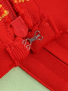 Gros plan du tissu en maille rouge avec fermeture à crochet argenté et détail de zip