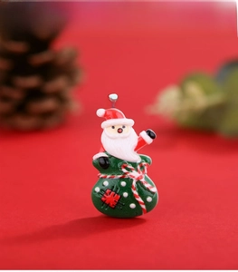 Detailed view of resin Santa pendant in green gift bag on festive red background