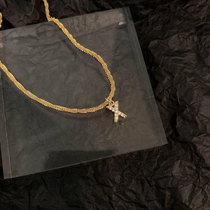 Vue macro d'un collier en titane doré avec pendentif Lettre X serti de zircons