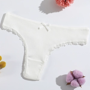 Detailed view of white ribbed lace thong with a delicate bow on a floral background