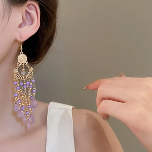 Detail showing Bohemian teardrop earrings with purple beads and golden metal tassels