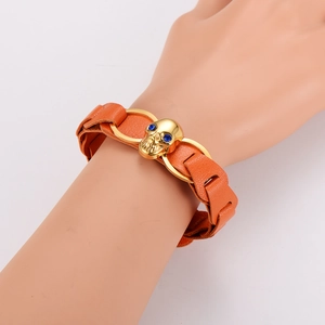 Orange braided leather bracelet with golden skull charm and blue eyes on a model