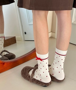 Detail of white mid-calf socks with red polka dots and a bow on a model with mirror view