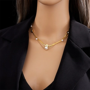 Dettaglio di una collana dorata a due strati con pendente di perle su una modella