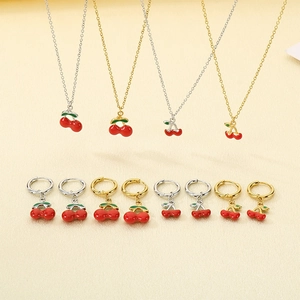Flat lay of cherry jewelry set featuring gold and silver enamel necklaces and earrings