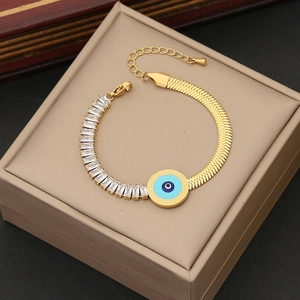 Detail of gold snake chain bracelet featuring blue evil eye charm and white baguette stones
