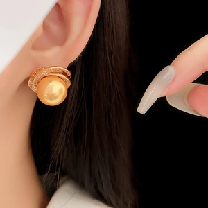 Close-up of vintage golden spiral earring with a large pearl and zircon accents on model