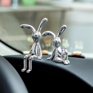 Duo kreativer silberner Hasenfiguren mit UV-Beschichtung auf schwarzem Auto-Armaturenbrett