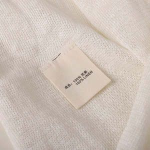 Macro shot of 100% linen knit fabric texture and care label for breathable beanie