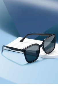 Detail of classic black square oversized sunglasses on a minimalist display stand