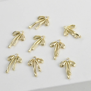 Detail of eight 14k gold-plated bow pendants with small crystals for jewelry making