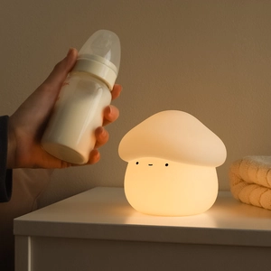 Rechargeable mushroom silicone night light for baby nursing on a warm bedroom bedside table