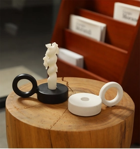 Minimalist ceramic ring candle holder in black and white finish on a rustic wood base