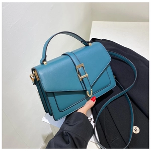 Close-up of blue crossbody bag with gold hardware buckle and sturdy top handle detail
