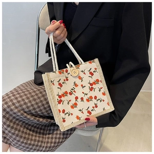 Detail of floral canvas tote bag featuring a rustic wooden button and rope handle