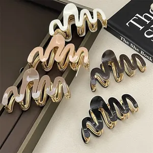 Detail shot of wavy acetate hair claws in five neutral colors on a premium leather tray