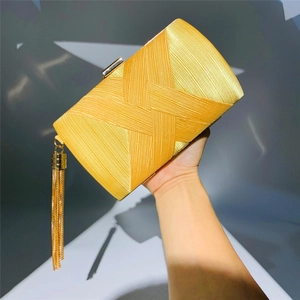 Detail of yellow woven satin evening clutch bag with gold tassel charm and metal clasp
