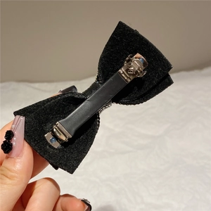 Detail of the black bow hair clip featuring a durable silver metal alligator clip with grip