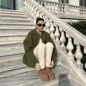 Outdoor street style view of olive green wool jacket with cream high-neck sweater
