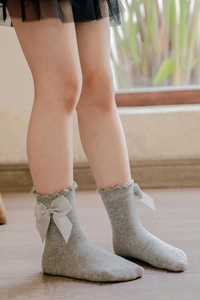 Close-up of girls' grey cotton socks with delicate ruffle edges and large ribbed bows