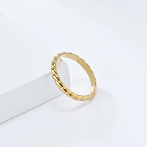 Close-up of a minimalist 18K gold braided twist ring on a clean geometric stand