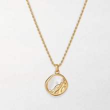 Detail of gold double-layer necklace with textured round pendant and white shell inlay
