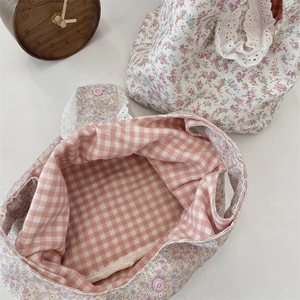 Close-up of floral canvas wrist bags featuring pink flower patterns and white lace trim