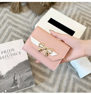 Close-up of pink leather wallet with white bow and golden metal butterfly clasp