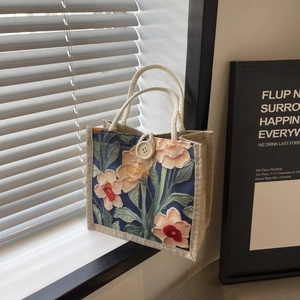 Detail of linen tote bag with floral print, rustic texture and beige button closure