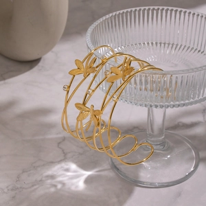 Detail of 18K gold-plated open bangle with dragonfly and butterfly charms in light