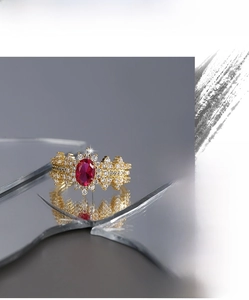 Macro shot of oval red ruby ring with pavé diamond cluster on golden metal band