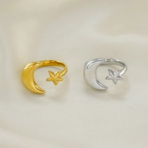 Gold and silver moon and star open rings on beige silk fabric background