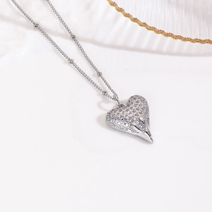 Macro shot of silver heart pendant necklace with cubic zirconia and beaded chain detail