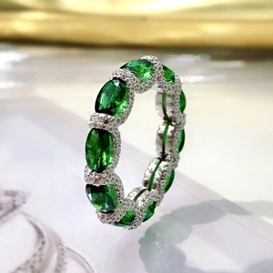 Close-up of elegant silver ring featuring oval emerald green stones and diamond accents