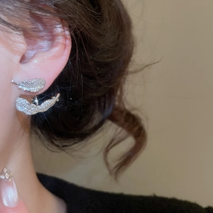Macro shot of silver feather earrings with zircon stones and tiered design on a model